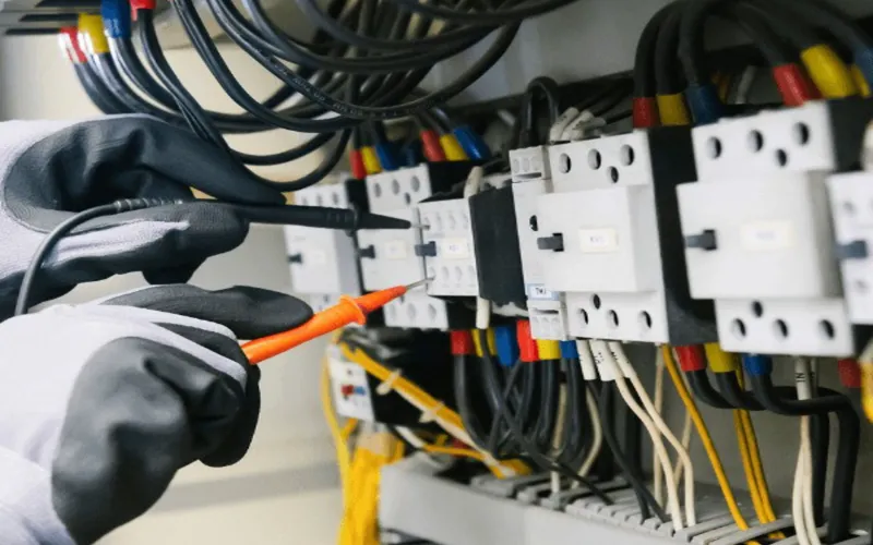 Electrician testing an electrical breaker panel with a multimeter