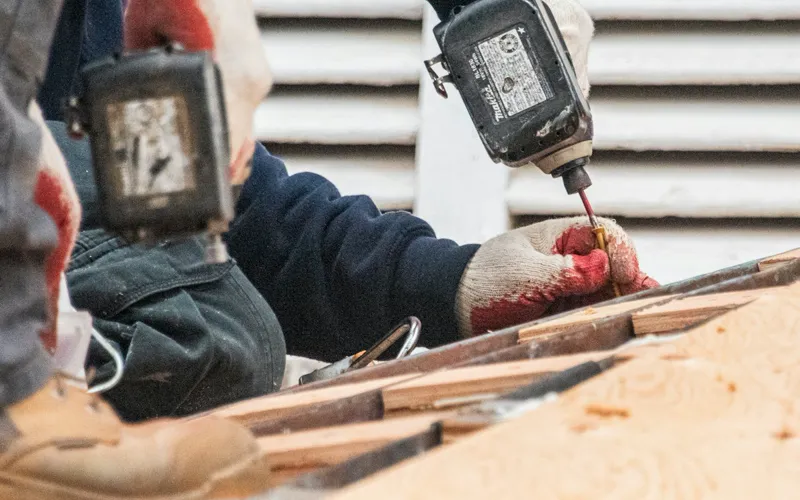 Roofing contractor fastening roof decking with a power driver
